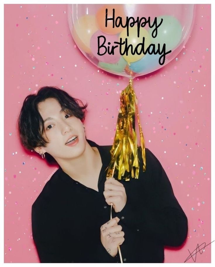 a young man holding a balloon with the words happy birthday on it in front of a pink background