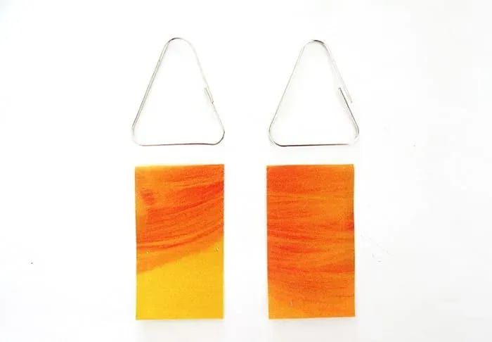 pair of orange and yellow rectangular earrings on white background with clipping for ear hooks