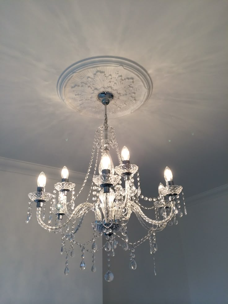 a chandelier hanging from the ceiling in a room with white walls and ceilings