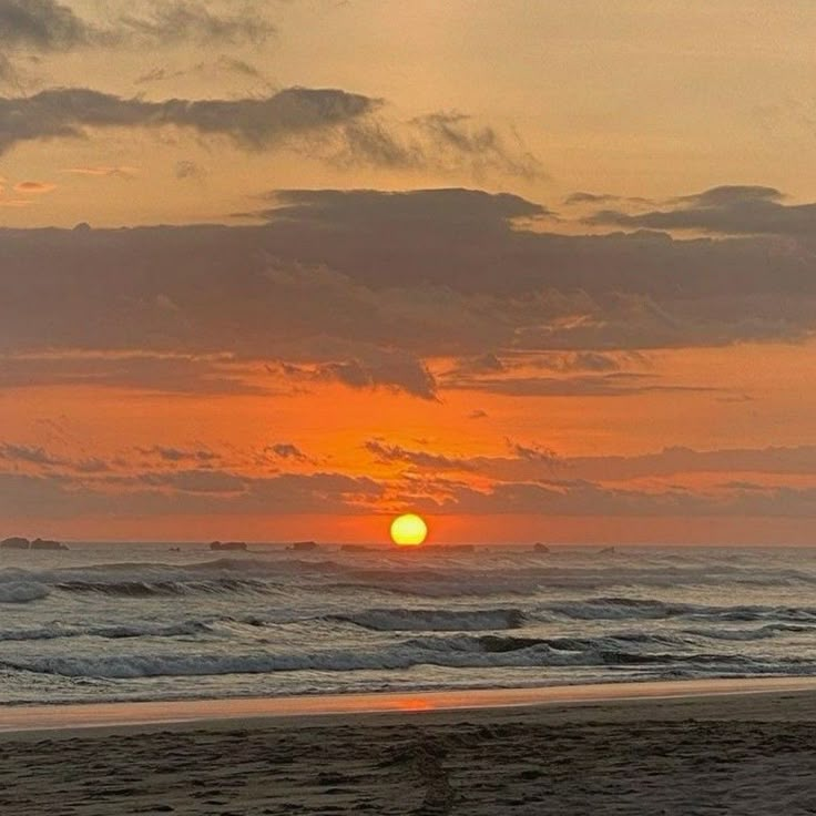 the sun is setting over the ocean at the beach