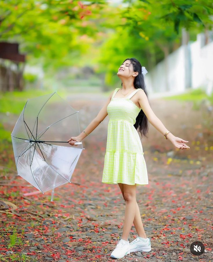 a woman in a yellow dress is holding an umbrella and looking up at the sky