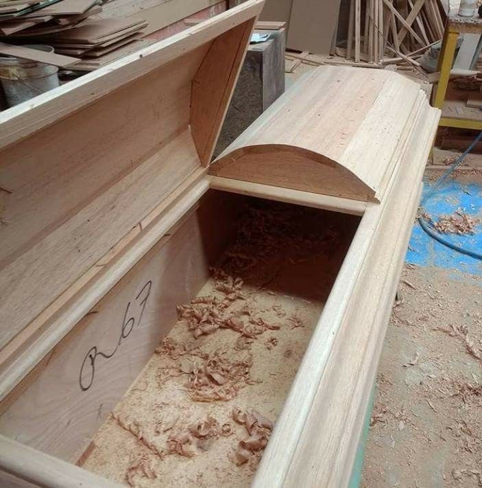 an open wooden box sitting on top of a pile of wood shaving and plywood