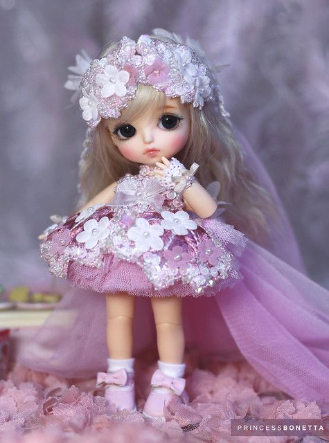 a doll is dressed in pink and white with flowers on her head, dress and shoes