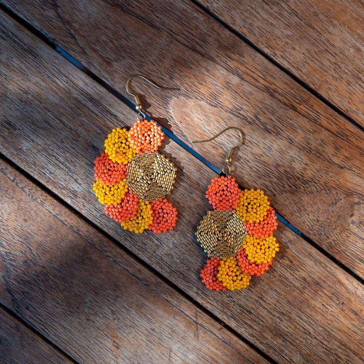 two pairs of beaded earrings sitting on top of a wooden table