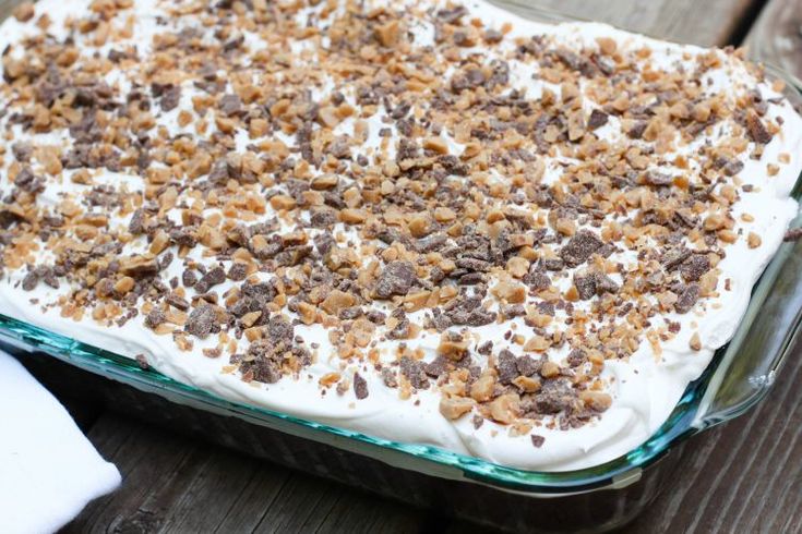 a dessert dish with white frosting and chocolate chips on top, sitting on a wooden table