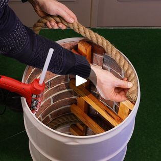 a person holding a rope in a bucket filled with bricks and water on the ground