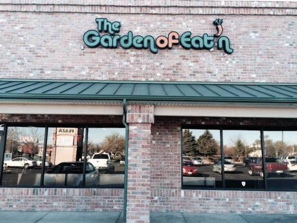 the garden of eat n store front with cars parked outside