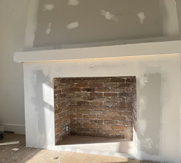 a brick fireplace in the middle of a room being remodeled with white paint on it