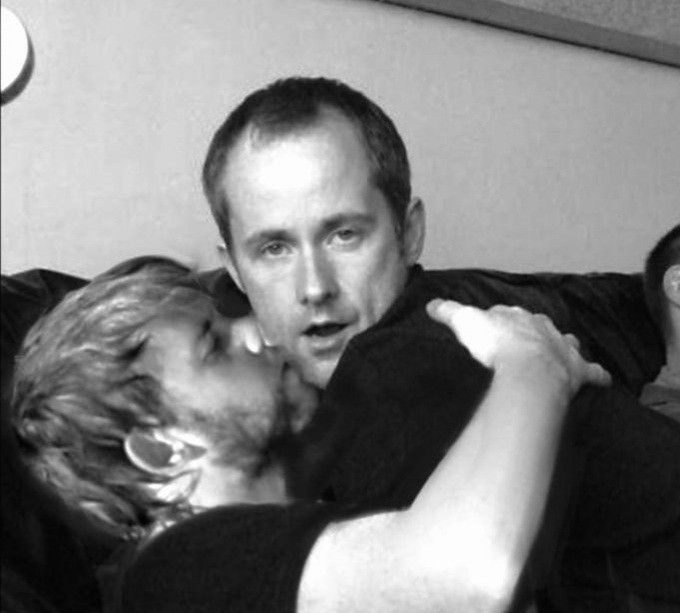 black and white photograph of two people laying on a couch with their arms around each other