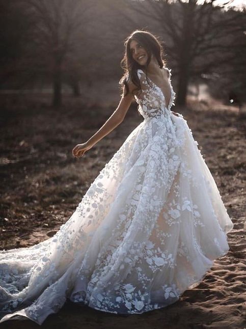 a woman in a wedding dress is standing on the ground with her arms out and hands behind her back