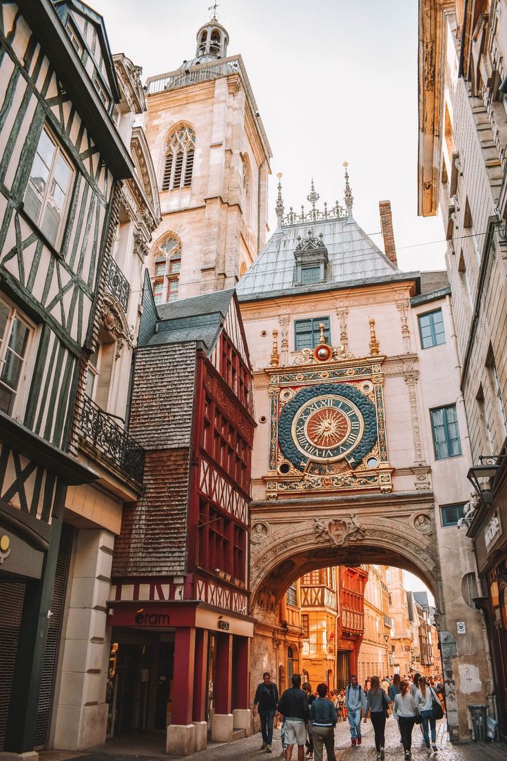 people are walking under an archway in the middle of a street with buildings on both sides