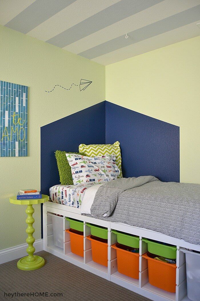 a bed with colorful storage bins underneath it in a room that is painted yellow and blue