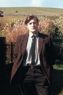 a man in a suit and tie standing next to a fence