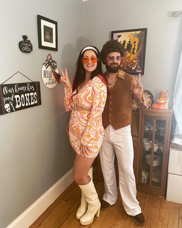 a man and woman dressed up in costumes posing for a photo with fake props on the wall behind them