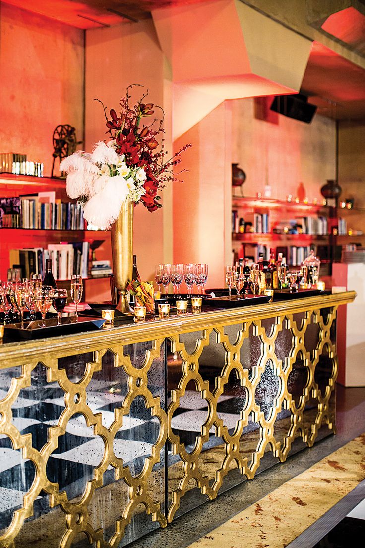 a gold bar with flowers and candles on the counter in front of bookshelves