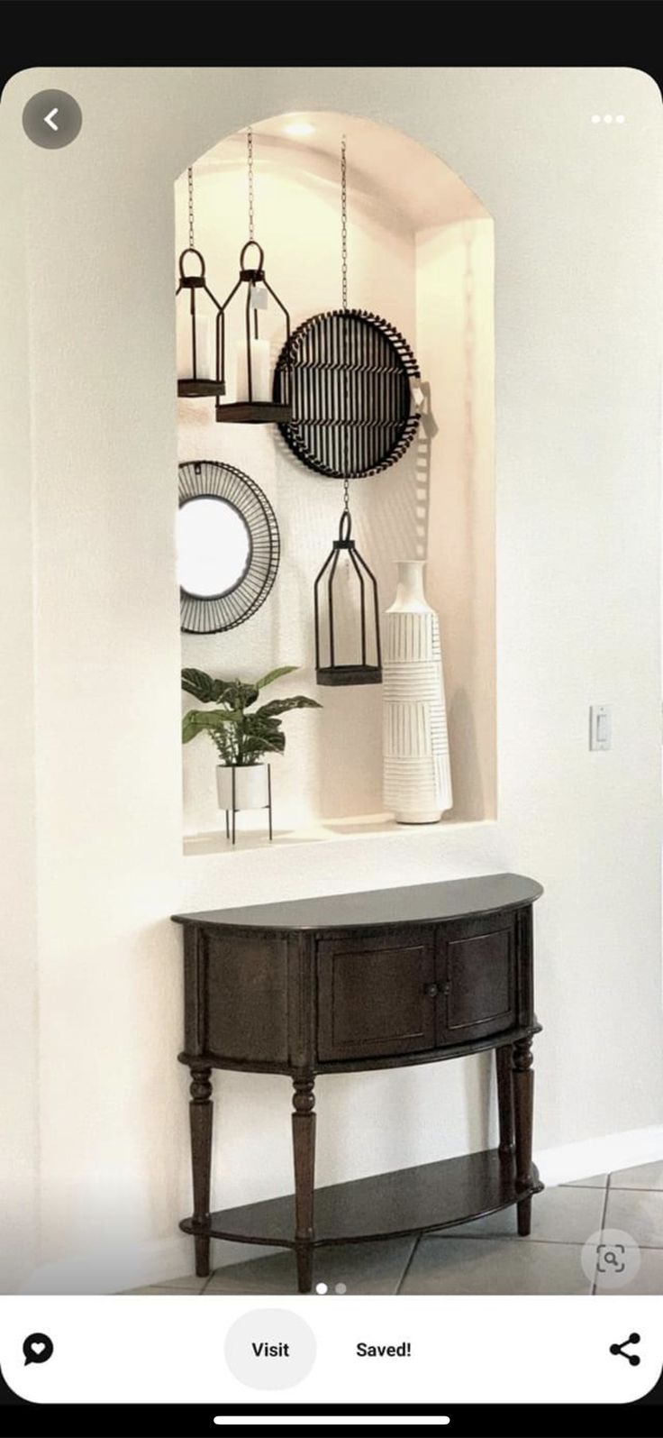 an entryway with a table, mirror and vases on the wall above it