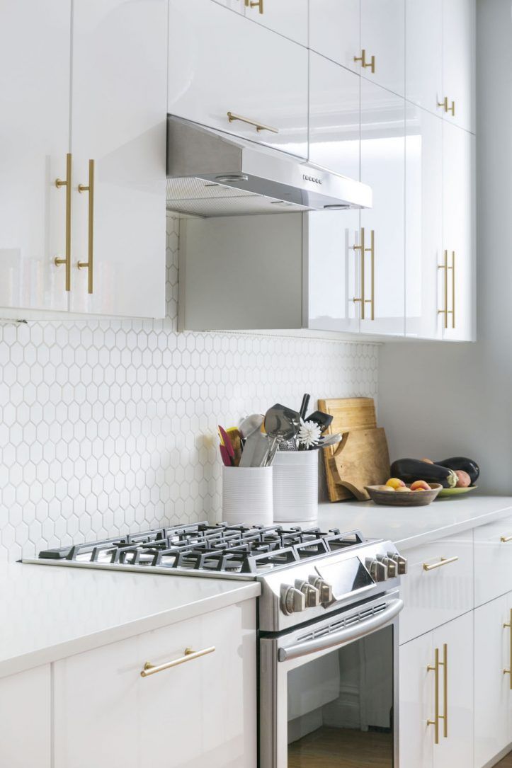 a stove top oven sitting inside of a kitchen next to white cupboards and drawers