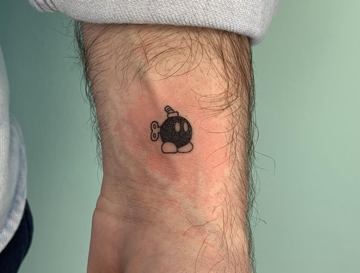 a small black cat tattoo on the wrist