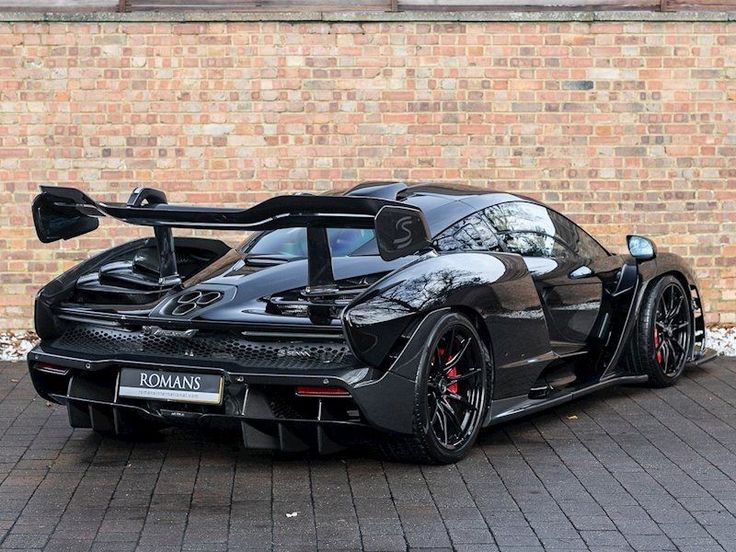 a black sports car parked in front of a brick wall