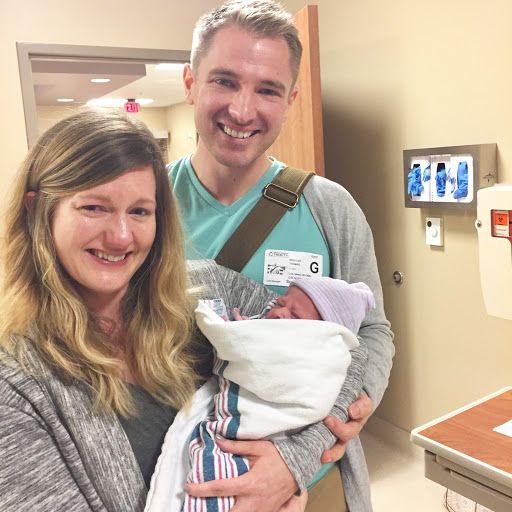 a man and woman holding a baby in a hospital room