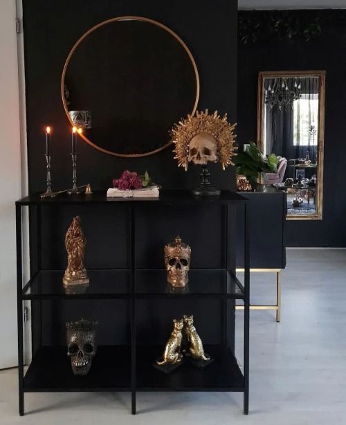 there is a black shelf with skulls on it and candles in front of the shelves