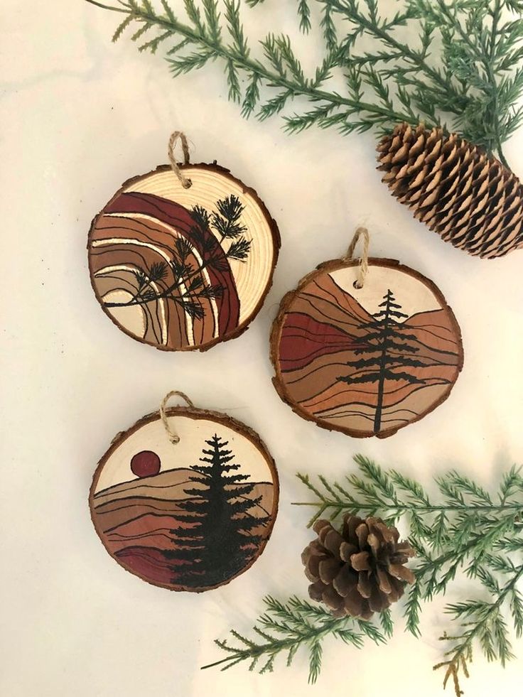 three wood burned ornaments with pine cones and evergreen needles