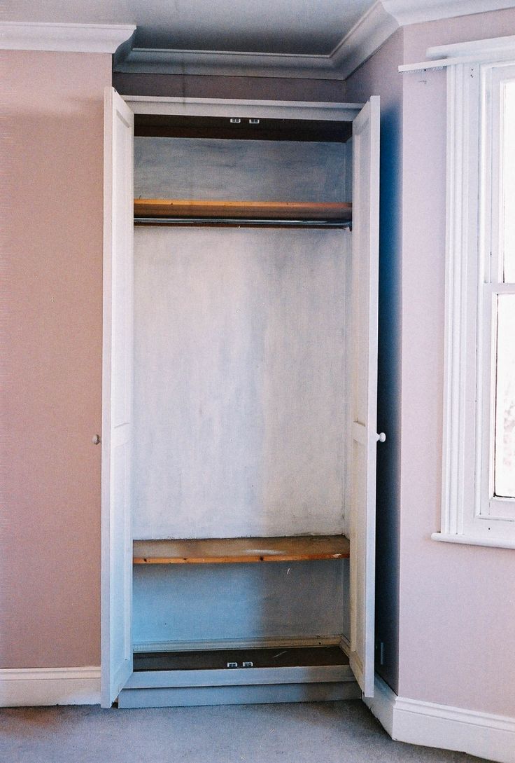 an empty walk in closet next to a window with no curtains on the door and shelves