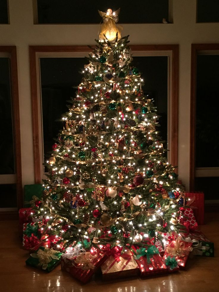 a lit christmas tree with presents under it