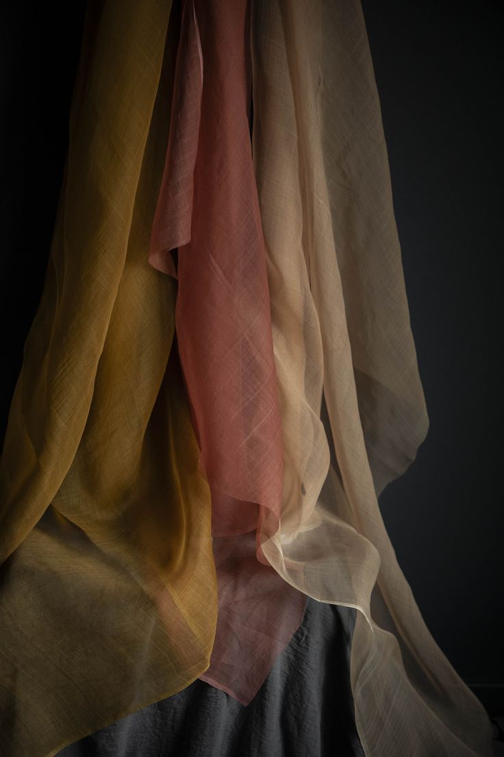 the sheer fabric is hanging up in front of a black background with light coming through it