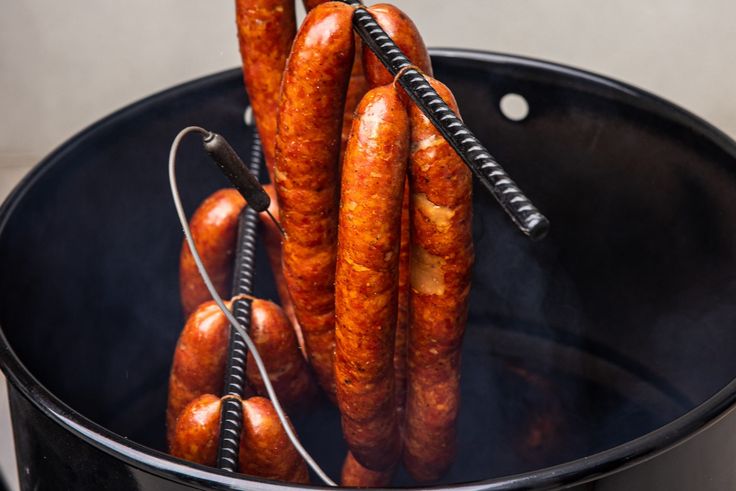 several sausages are being cooked in a black pot with a cord attached to them