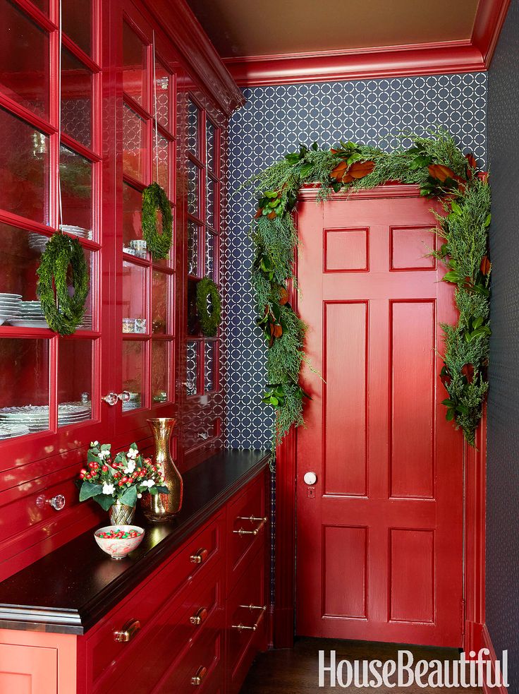 an instagram photo with christmas wreaths on the front door and red cupboards