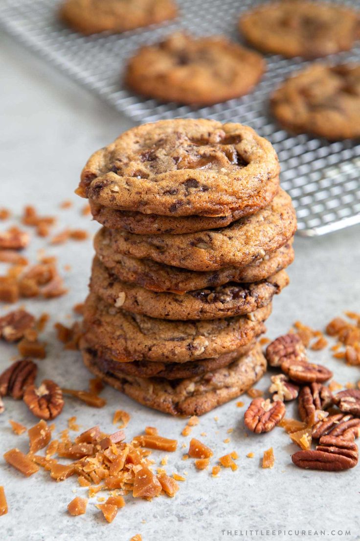 chocolate chip cookies stacked on top of each other with pecans scattered around the cookie