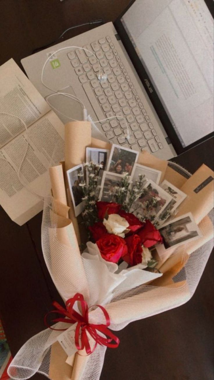 a bouquet of flowers and pictures is sitting on a desk next to a laptop computer