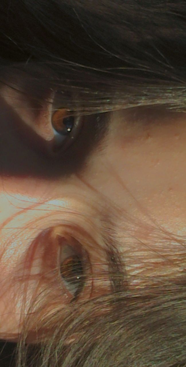 a person's eye is reflected in the reflection of another persons face with long hair