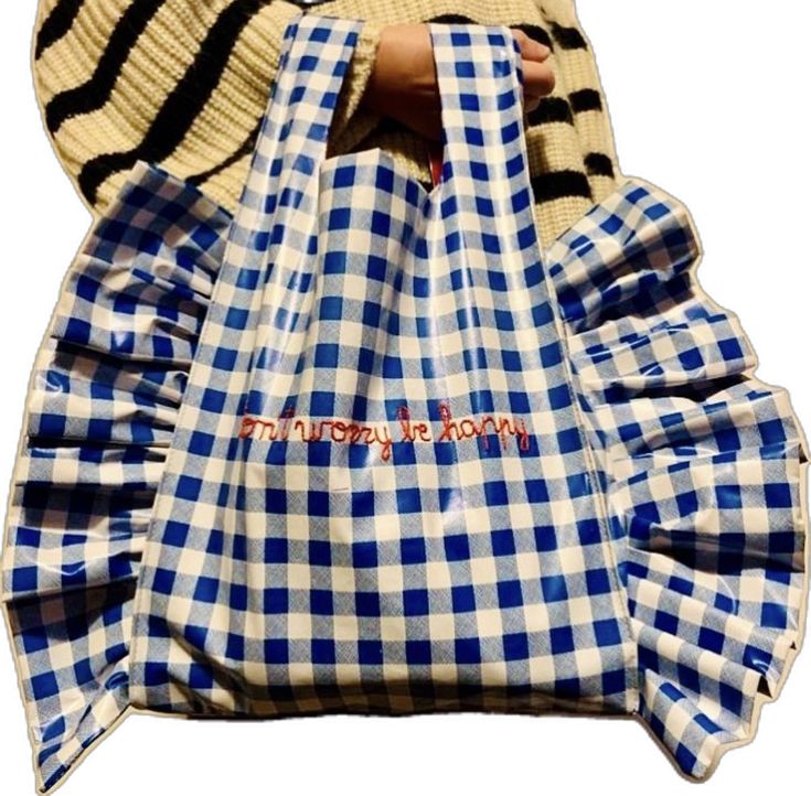 a hand holding a blue and white checkered bag