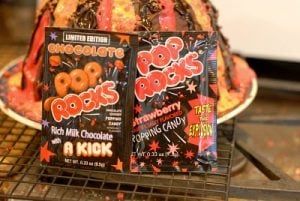 two bags of chocolate pop rocks sitting on top of a rack in front of a cake