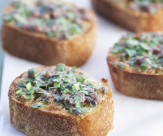 several pieces of bread with various toppings on them sitting on a white plate, ready to be eaten