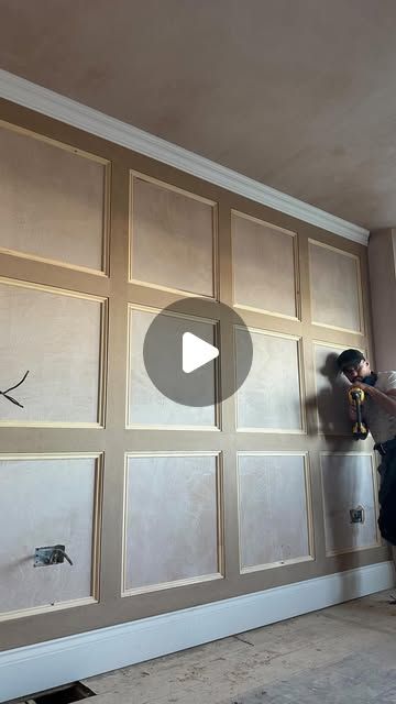 a man is painting the walls in an empty room with wood paneling and white paint