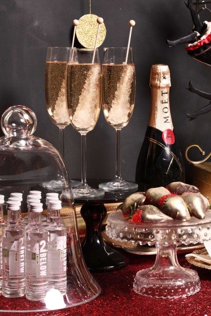 two glasses of champagne are sitting on a table next to some bottles and trays