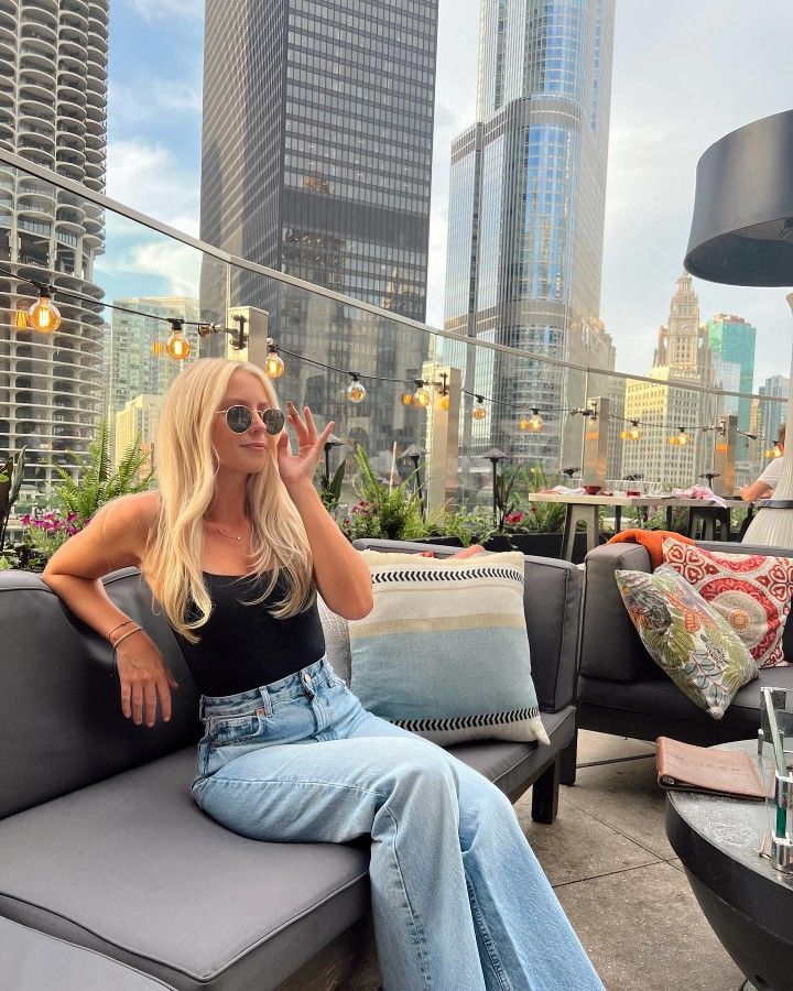 a blonde woman sitting on top of a couch next to tall buildings in the city