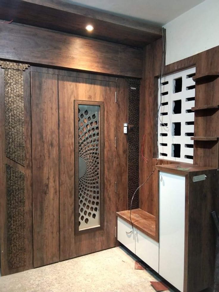 a room with wooden paneling and white cupboards in the corner, along with a shelf on the wall