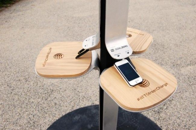 two cell phones are plugged into an electronic device holder on a pole in the street