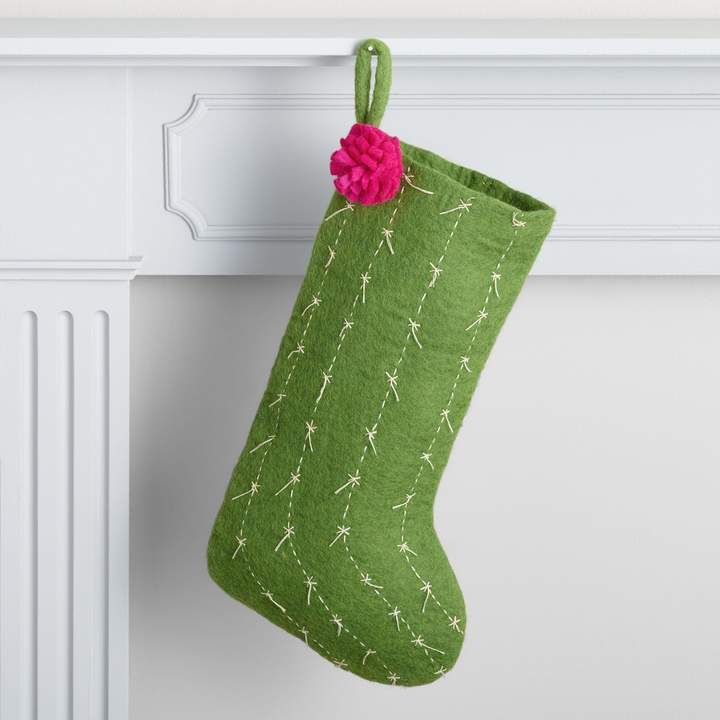 a green christmas stocking hanging from a white mantle with a pink flower on it