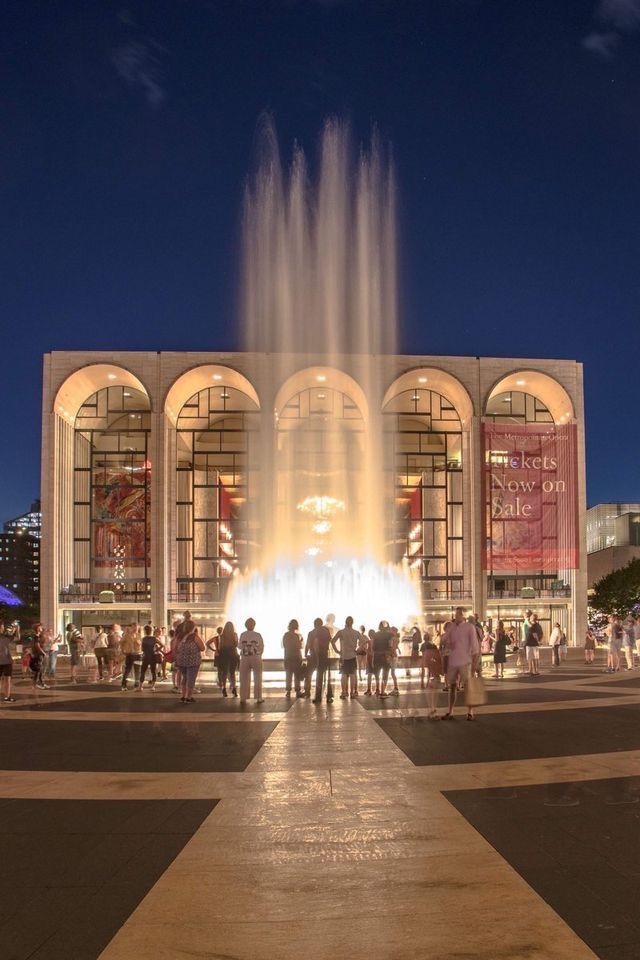 people are standing around in front of a fountain