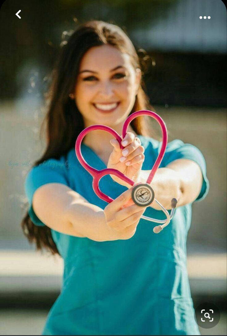 a woman holding a stethoscope in the shape of a heart and smiling