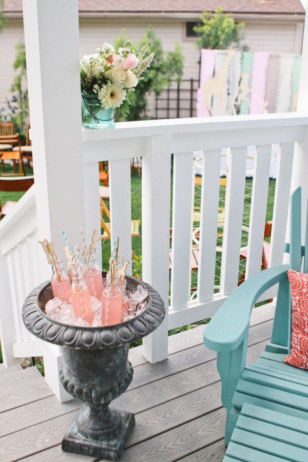 an outdoor table with drinks on it sitting on a porch next to a blue chair