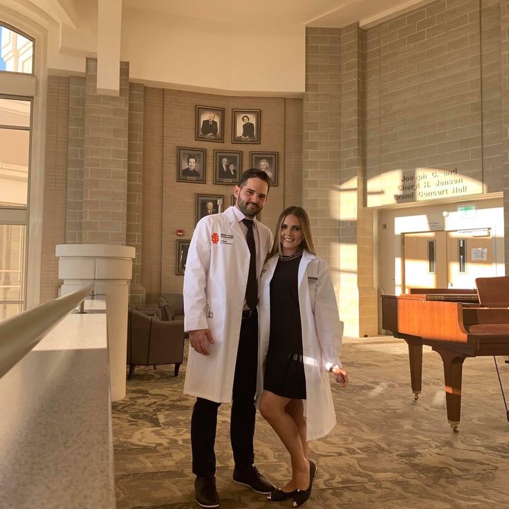 a man and woman standing next to each other in front of a piano