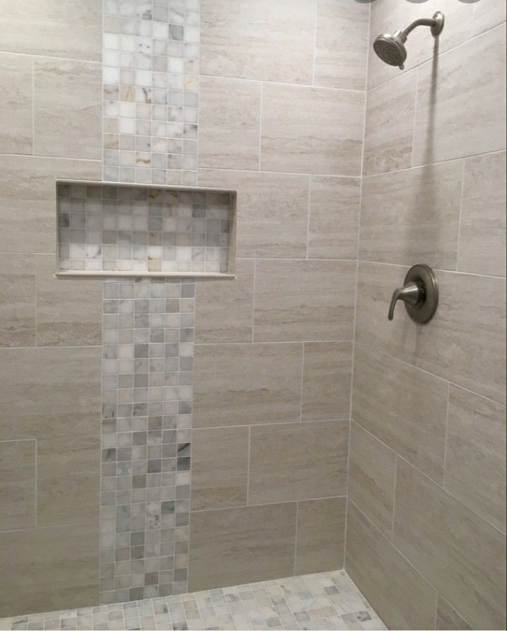 a walk in shower sitting next to a tiled wall