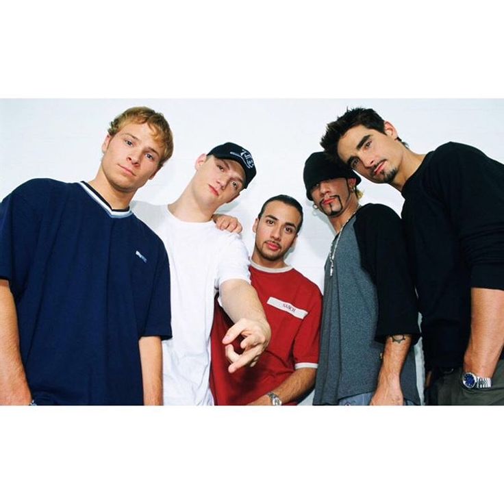 four young men are posing for the camera with their arms around each other and pointing at something