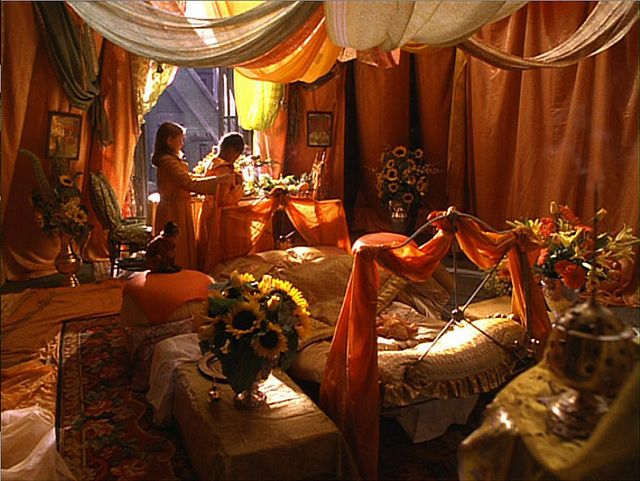 a living room filled with lots of furniture and flowers on top of the couches